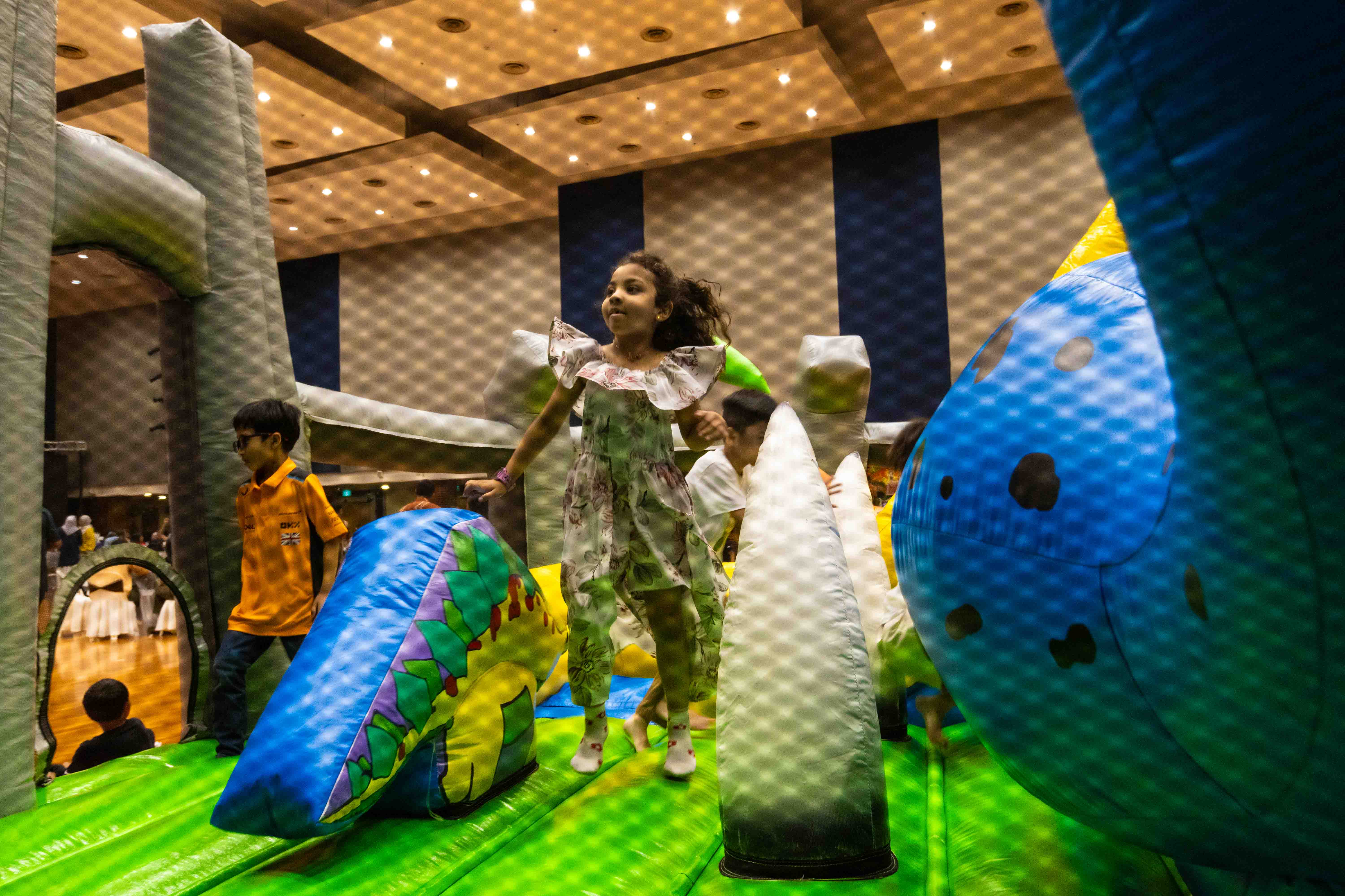 View of a young girl jumping on the inflatable obstacle course through netting.
